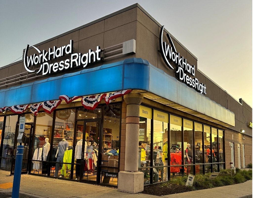 Exterior of the Work Hard Dress Right store in Newark, NJ, at sunset, showcasing uniforms, workwear, and safety apparel through the storefront windows.
