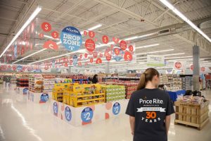 Emploee wearing a Price Rite 30th Anniversary t-shirt inside a brightly decorated supermarket.