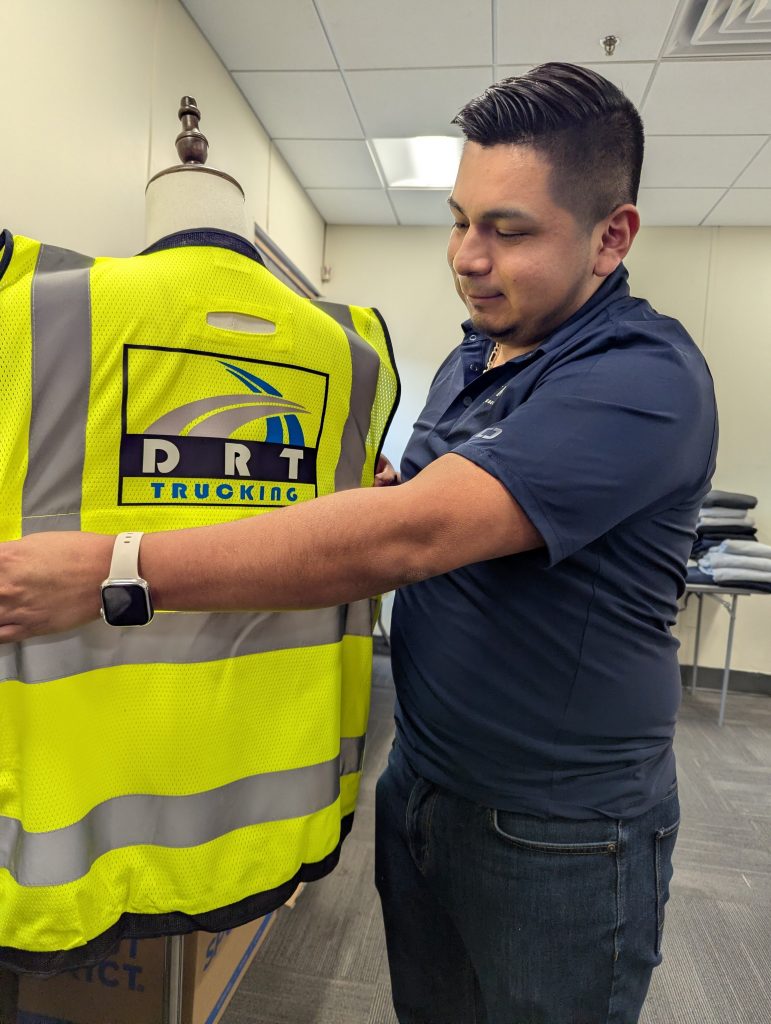 Graphic designer at Feury Image Group adjusting logo placement on a high-visibility safety vest for a managed uniform program.