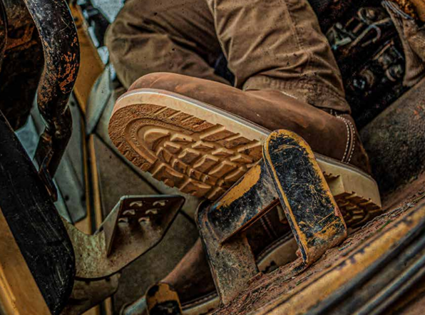 work boot outsole gripping construction equipment pedal on muddy jobsite