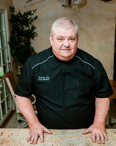 Executive chef wearing a black custom embroidered chef coat representing professional workwear and branding