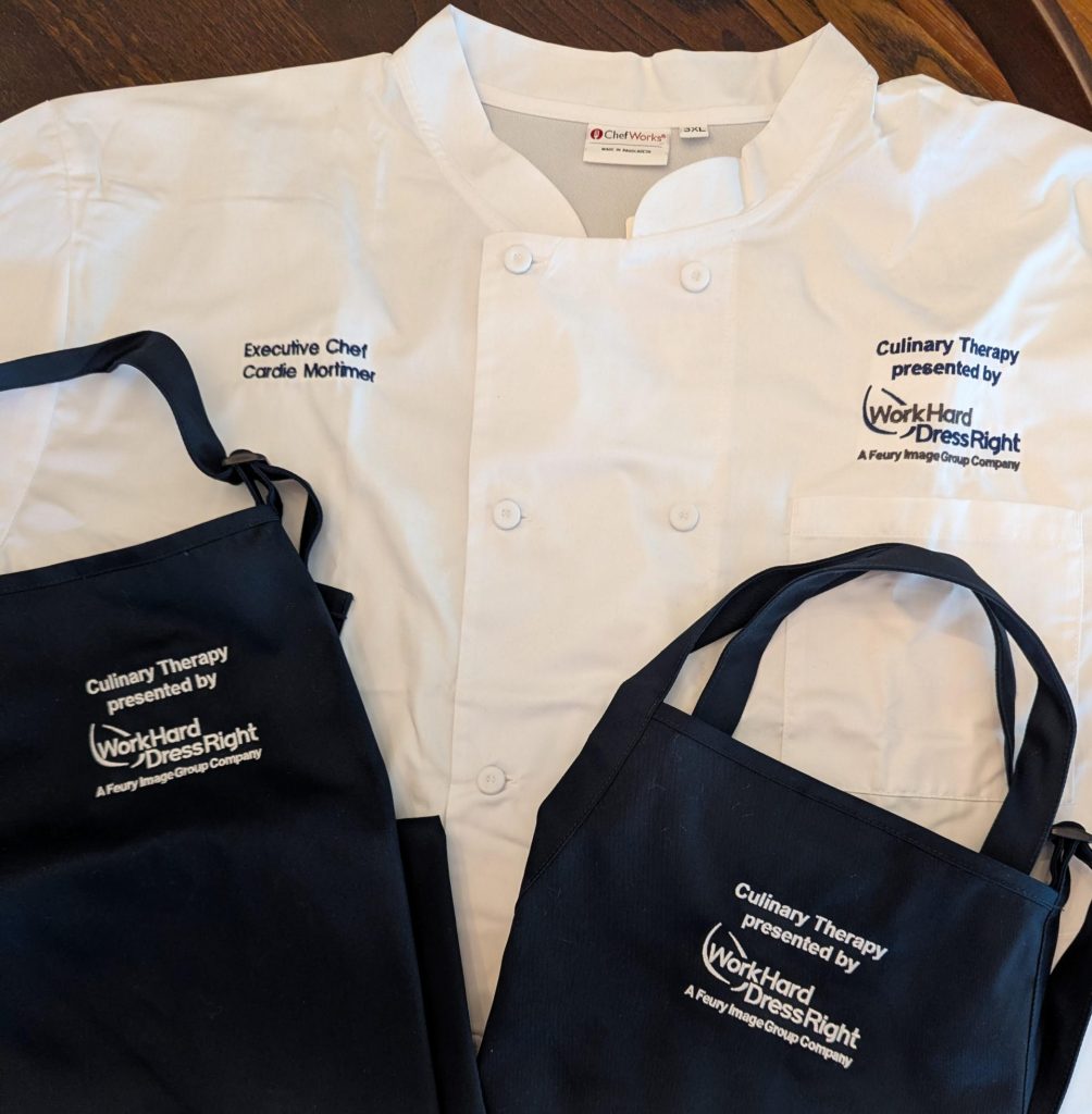 Custom embroidered chef coat and aprons for Chef Cardie Mortimer featuring Culinary Therapy and Work Hard Dress Right branding