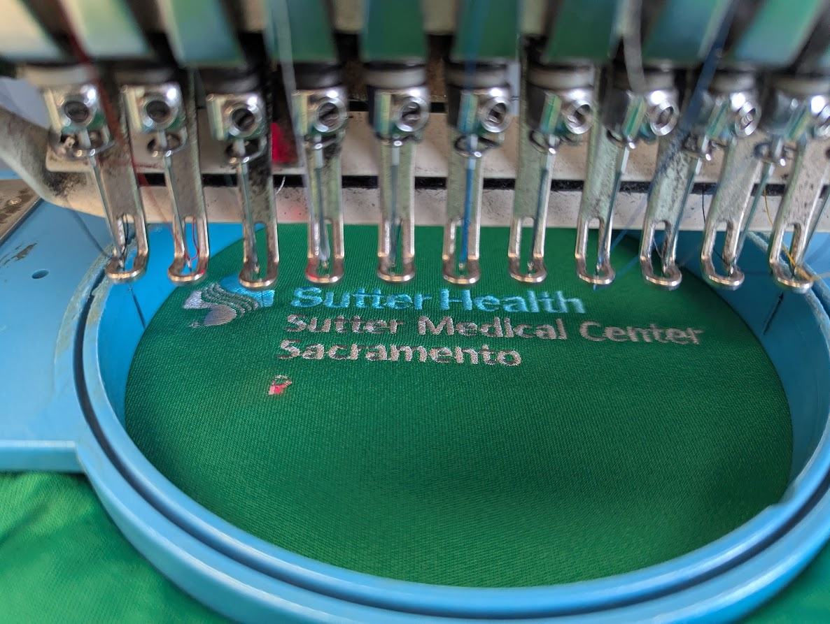 Embroidery machine applying a healthcare organization logo to apparel